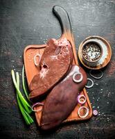 Raw liver on a cutting Board with onions and spices. photo