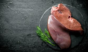 Raw liver with dill on a stone Board. photo