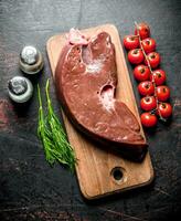 Piece of raw liver on a wooden cutting Board. photo