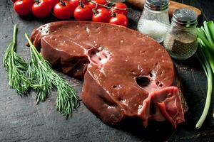 Fresh raw liver with dill, spices and tomatoes. photo