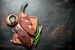 Raw liver on a cutting Board with onions and spices. photo