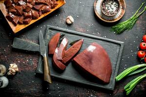 Sliced raw liver on a cutting Board with a knife. photo