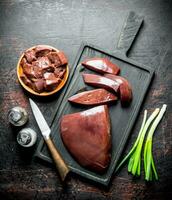 Pieces of raw liver in a plate and on a cutting Board. photo