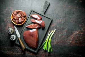 Pieces of raw liver in a plate and on a cutting Board. photo