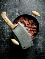 Sliced raw liver in a saucepan with a big knife. photo