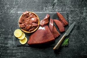 Sliced raw liver on a stone Board and on a plate. photo