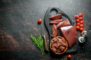 Raw liver with cherry tomatoes, spices and dill on a cutting Board. photo