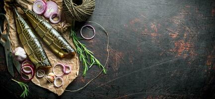 Fragrant smoked mackerel on paper with twine and chopped onion. photo