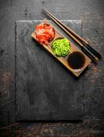 Ginger, wasabi and soy sauce on a wooden stand with chopsticks. photo