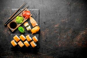 Philadelphia roll and various sushi with sauce on a stone Board. photo