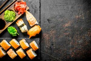 Philadelphia roll and various sushi with sauce on a stone Board. photo