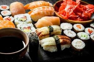 varios rollos, Sushi y maki en un Roca tablero con soja salsa y jengibre. foto