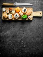 Sushi rolls with shrimp, vegetables and salmon on a cutting Board with a knife. photo