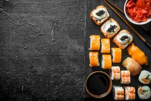 Traditional Japanese sushi rolls with ginger and soy sauce on a black stone Board. photo