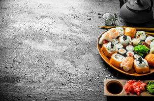 Delicious sushi rolls with shrimp, vegetables and salmon on a wooden plate. photo