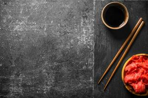 Soy sauce and marinated ginger on a stone Board with chopsticks. photo