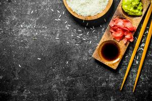 Ginger, soy sauce and wasabi on a stand with rice and chopsticks. photo