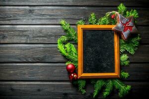 Empty Christmas photo frame with fir branches and decorations.