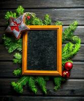 Empty Christmas photo frame with fir branches and decorations.