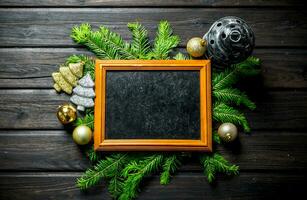 Photo frame with Christmas decorations and fir branches.