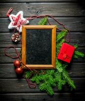 Photo frame with Christmas decorations and fir branches.