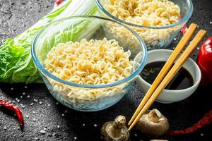 Instant noodles in bowls with mushrooms, Peking cabbage and soy sauce. photo