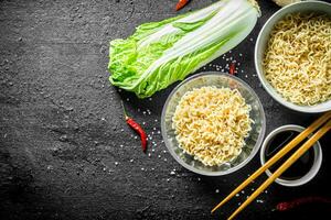 Instant noodles in bowls with Peking cabbage and soy sauce. photo