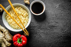 Instant noodles in bowl with bell pepper, ginger and soy sauce. photo