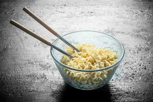 Heated instant noodles in glass bowl with chopsticks. photo