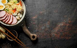 Fragrant instant noodles on a cutting Board with vegetables, ham and egg. photo