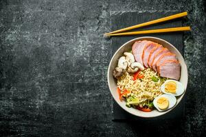 Instant noodles in bowl on stone Board with chopsticks. photo