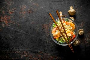 Instant noodles in a glass bowl with shrimp, vegetables and mushrooms. photo