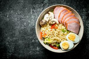Instant noodles in bowl with broccoli, mushrooms, becon and egg. photo
