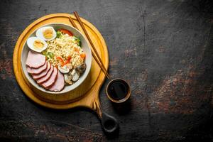 Instant noodles in bowl on cutting Board with becon, egg and mushrooms. photo