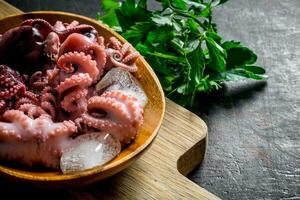 Small octopus on a cutting Board with pieces of ice and parsley. photo