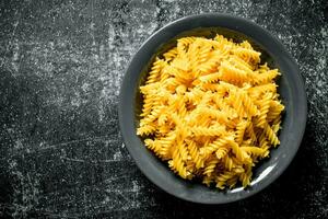 Dry fusilli pasta in a bowl. photo