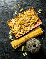 An assortment of different types of pasta dry on a plate with twine. photo