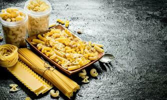 Different types of dry pasta on the plate and in bowls. photo