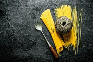 Dry spaghetti with twine and ladle. photo