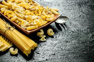 Assortment of different types of dry pasta with ladle. photo