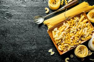 Assortment of different types of dry pasta on a plate with ladle. photo