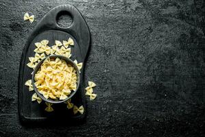 Farfalle pasta dry in a bowl on a cutting Board. photo