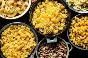 Different types of dry pasta in bowls. photo
