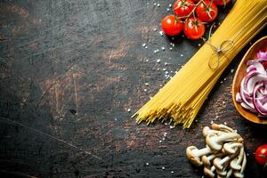 crudo espaguetis con Tomates, hongos y corte cebolla en bol. foto