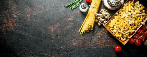 Different types of raw pasta with tomatoes, spices and mushrooms. photo