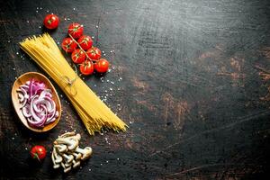 Raw spaghetti with tomatoes, mushrooms and cutting onion in bowl. photo