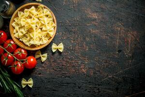 Raw Farfalle pasta in a bowl with the tomatoes, rosemary, mushrooms and spices. photo