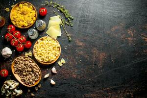 Different types of raw paste in bowls with tomatoes, garlic and mushrooms. photo