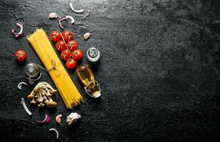 Raw spaghetti with onion slices, tomatoes, mushrooms and oil in a bottle. photo