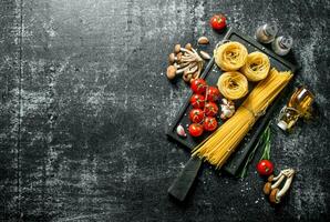 Raw tagliatelle and spaghetti with mushrooms, tomatoes and spices. photo